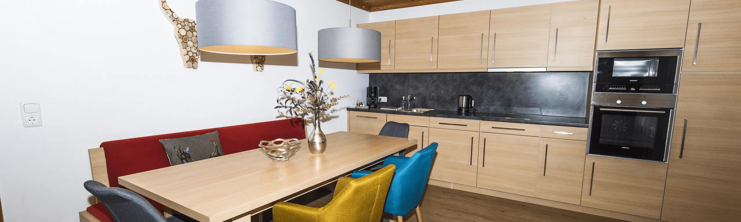 Moderne Küche mit einem Holztisch und bunten Stühlen