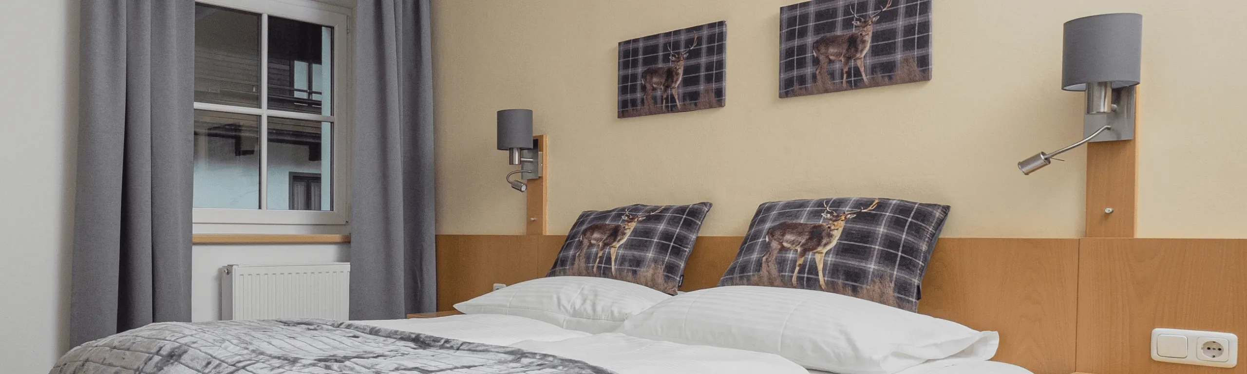 Schlafzimmer mit einem Doppelbett, zwei Wandleuchten und Kunstwerken über dem Bett