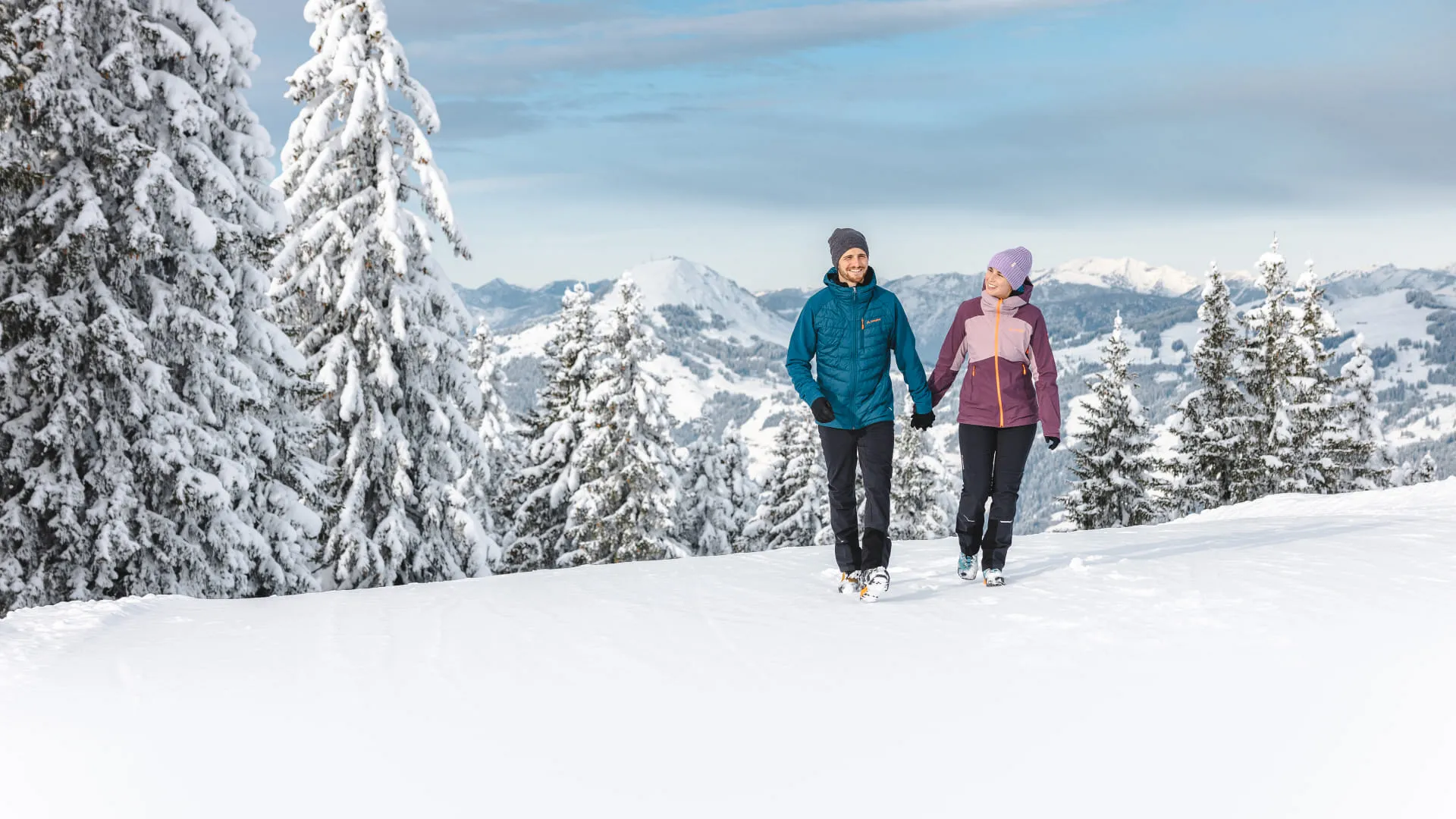 Zwei Personen wandern im Winter durch eine verschneite Landschaft in Brixental.