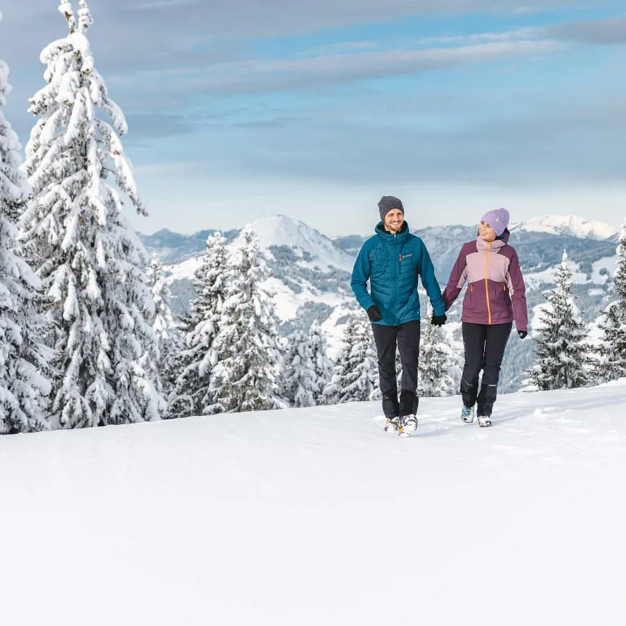 Zwei Personen wandern in verschneiter Winterlandschaft im Brixental