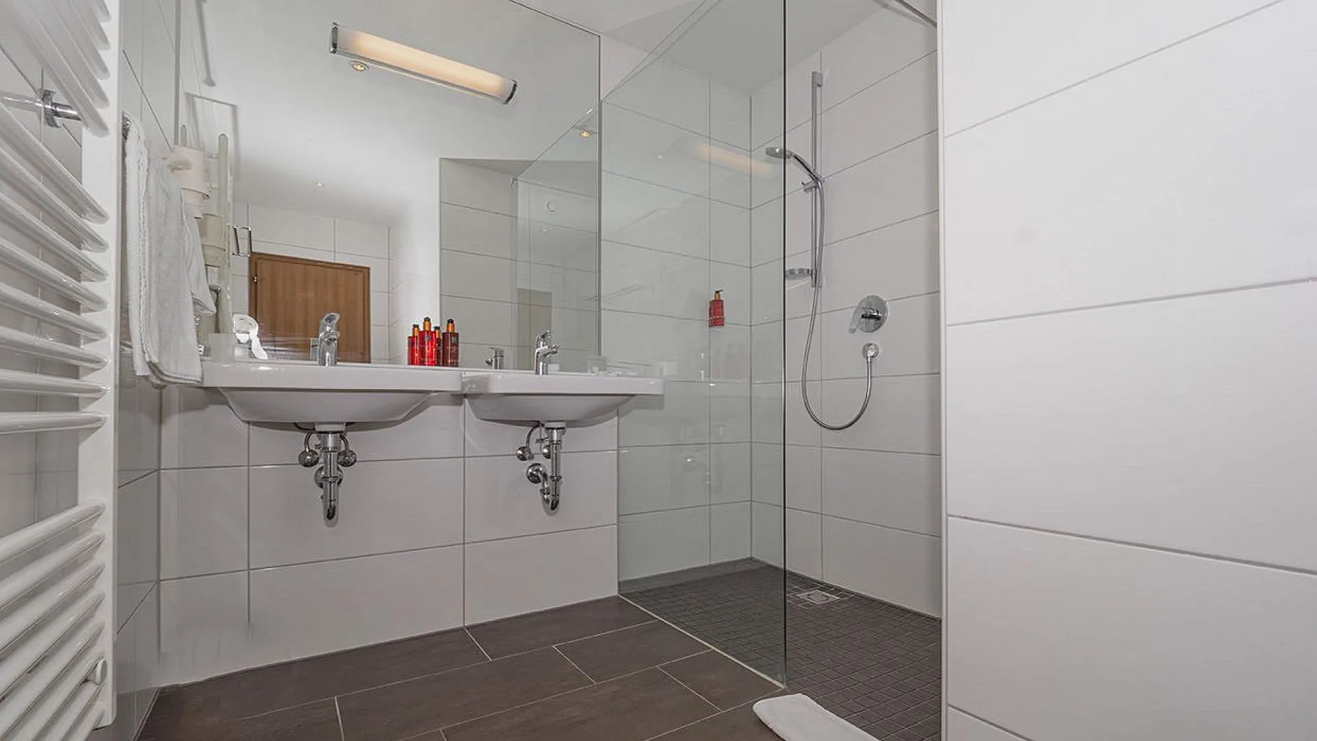 Helles Badezimmer mit zwei Waschbecken und einer Duschkabine