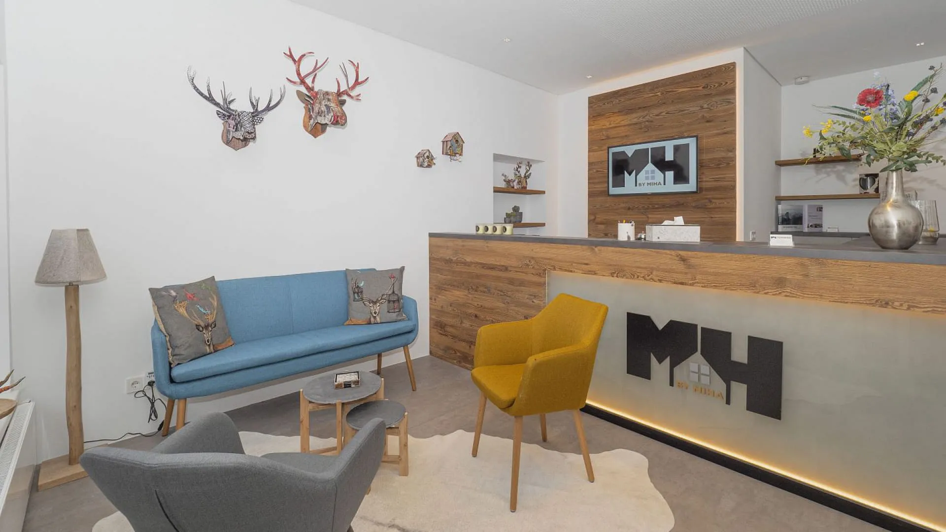 Moderne Empfangsbereich mit Sitzgelegenheiten und Dekor, Holzschreibtisch und Wandkunst.