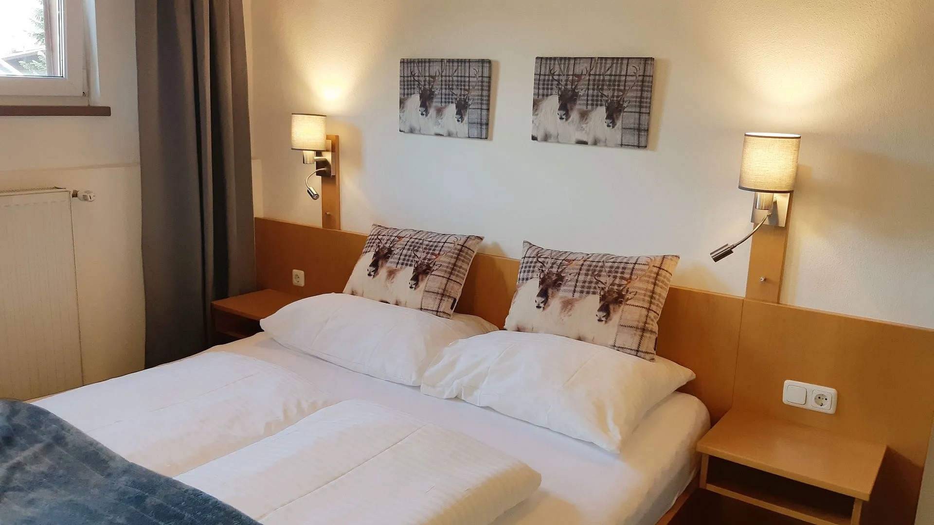 gemütliches Schlafzimmer mit zwei Betten, Kunstwerken an den Wänden und Nachttischlampen
