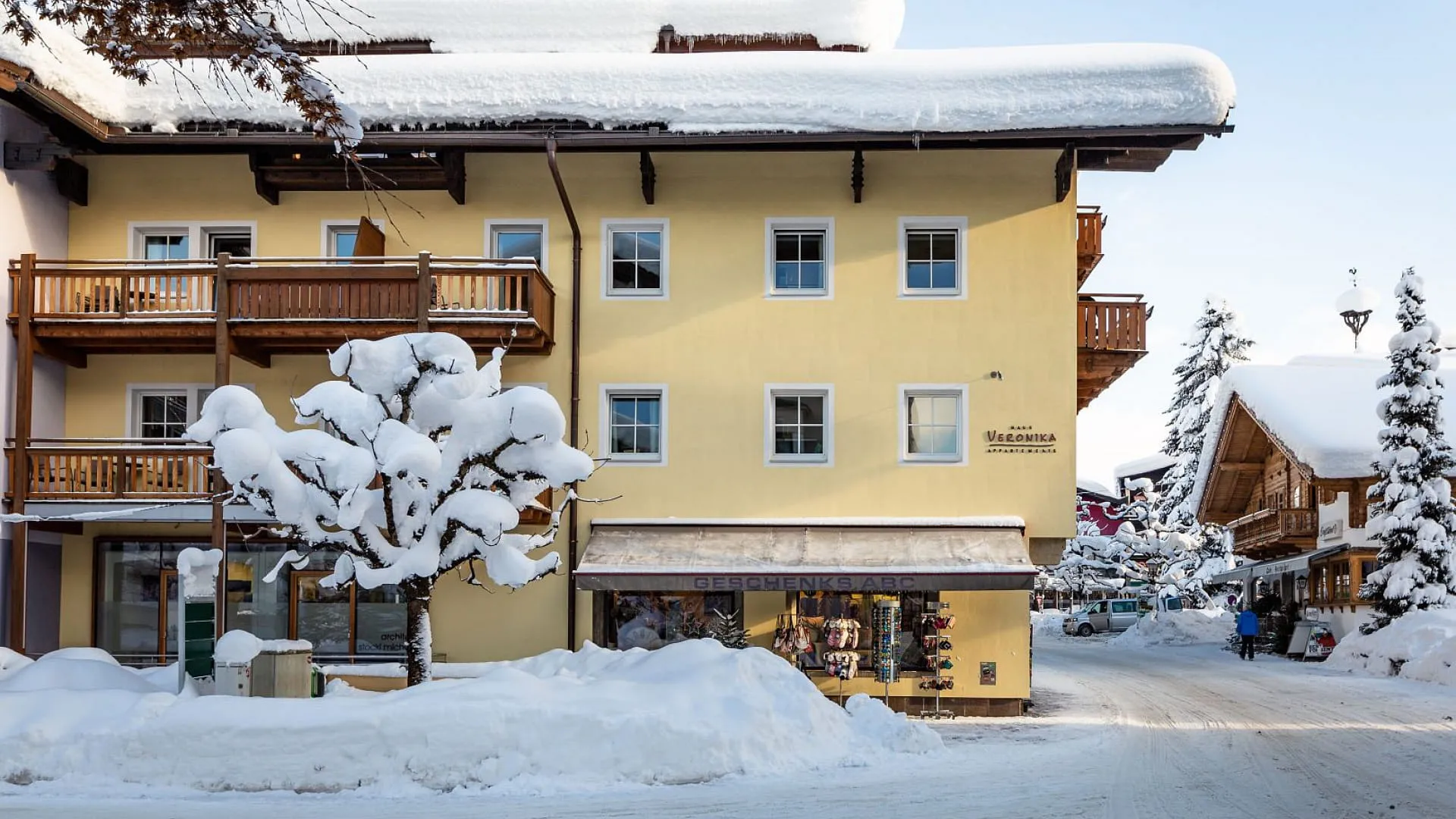 Schneebedeckte Gebäude mit Balkonen und einem verschneiten Baum