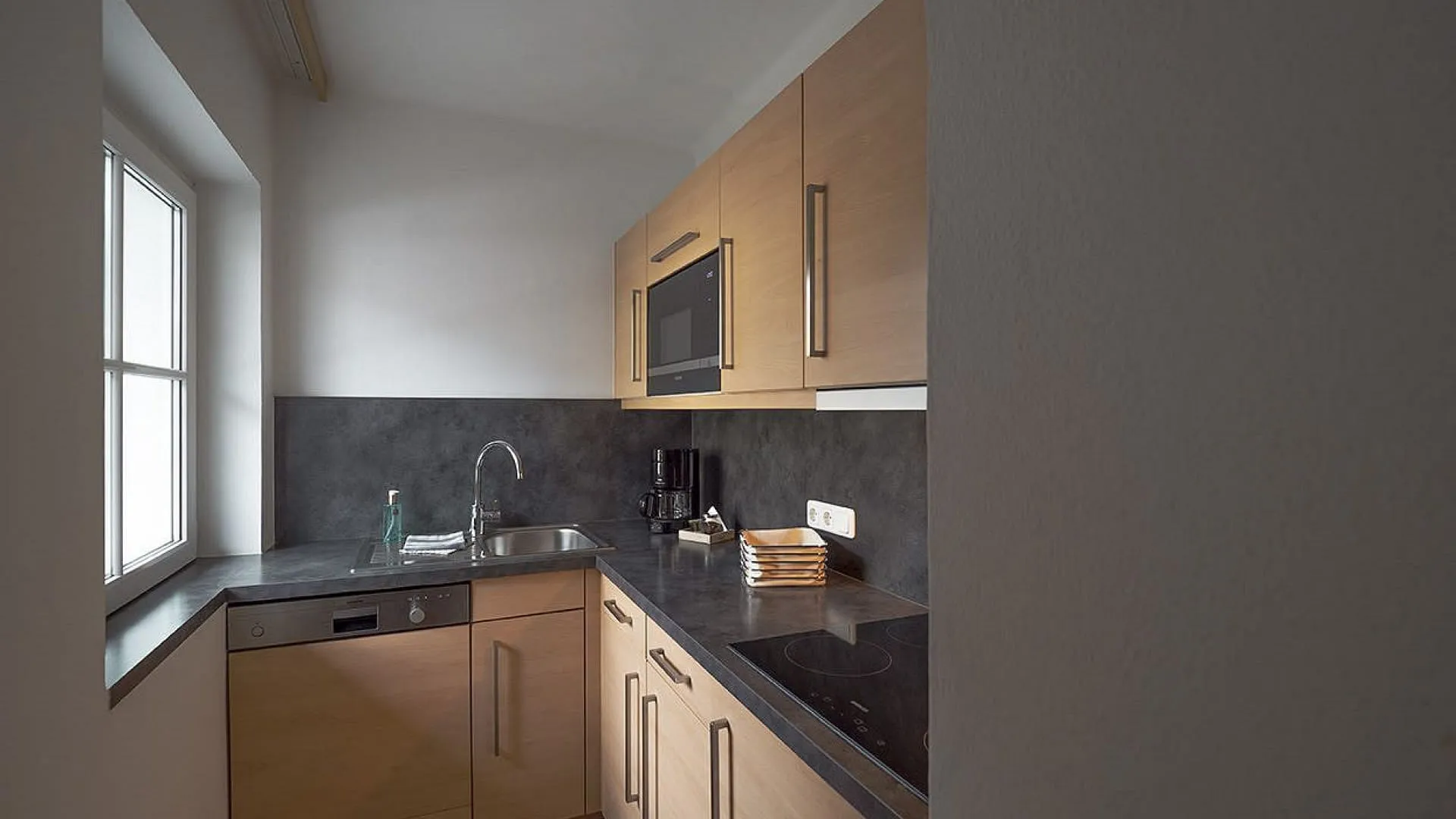 moderne Küche mit Holzmöbeln und dunklen Arbeitsplatten