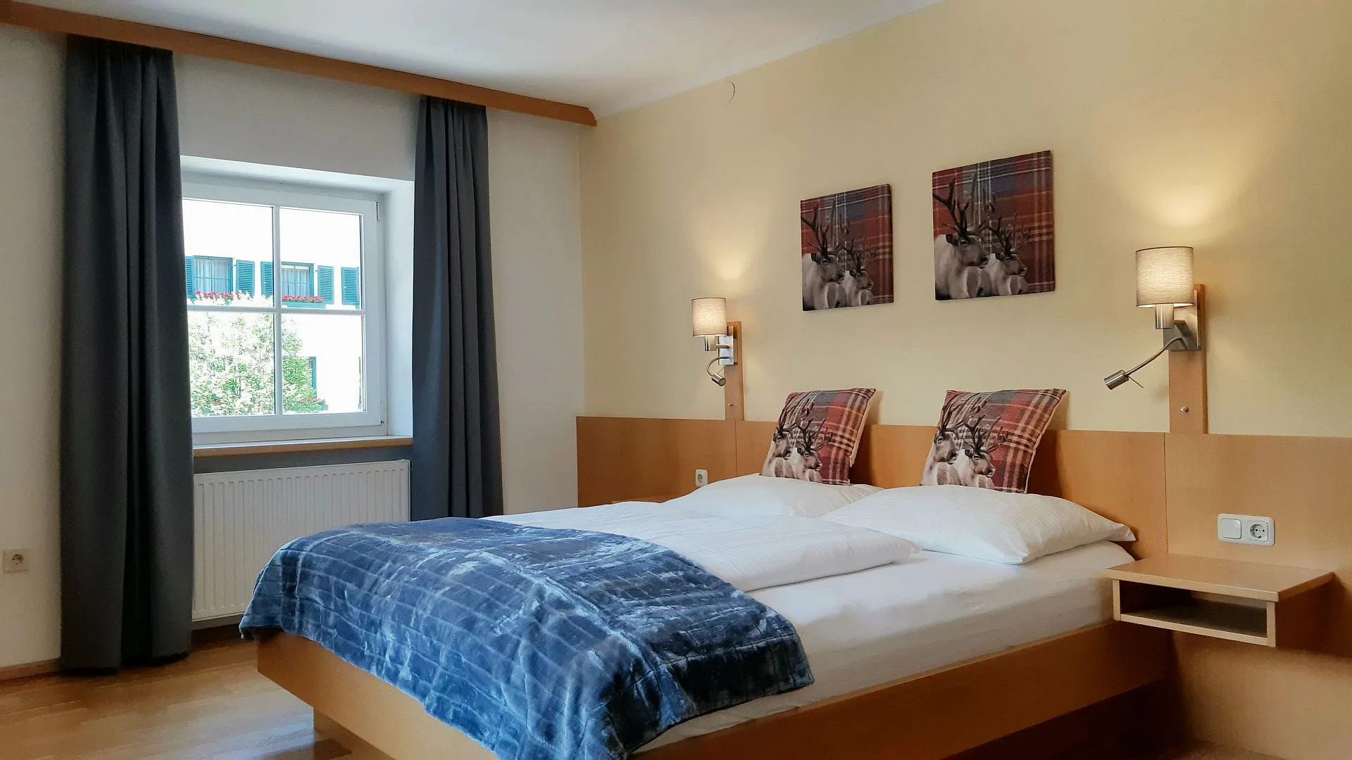 Helles Zimmer mit Doppelbett, Kunstwerken und Fensterblick.