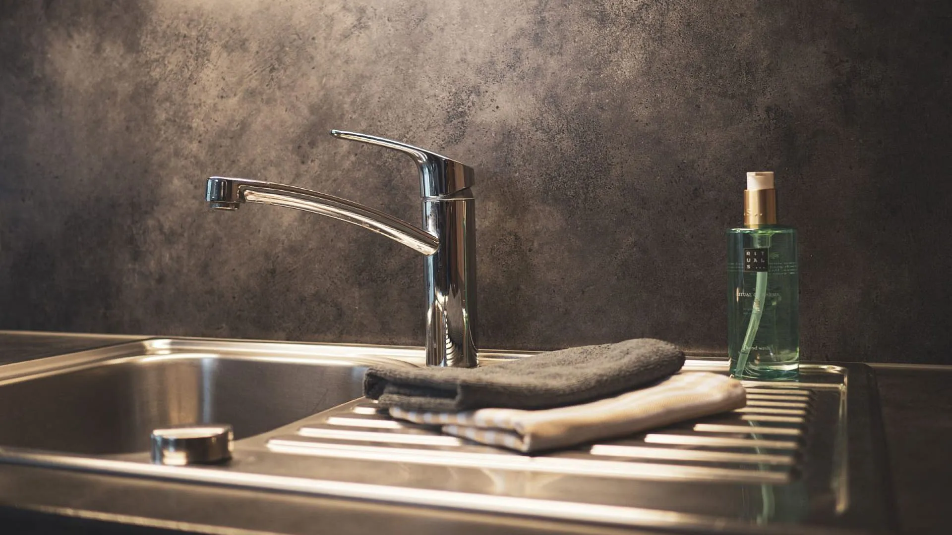 Moderne Küchenspüle mit Wasserhahn und Handtüchern