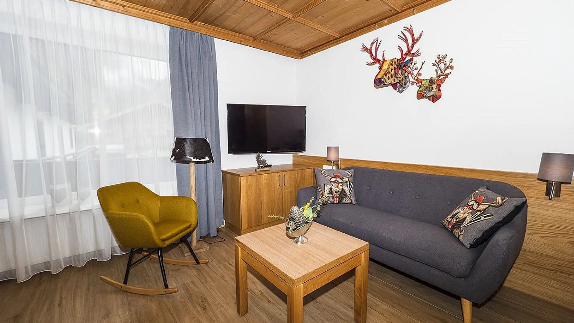 gemütlicher Wohnbereich mit Sofa, Schaukelstuhl, Fernseher und dekorativer Kunst