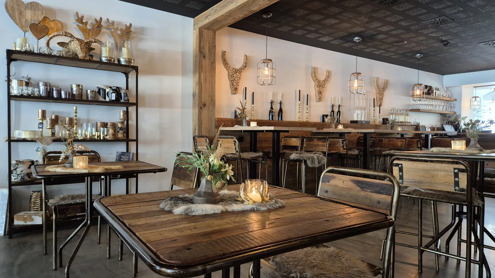 Ein gemütliches Restaurant mit Holztischen und einem Regal voller Deko.