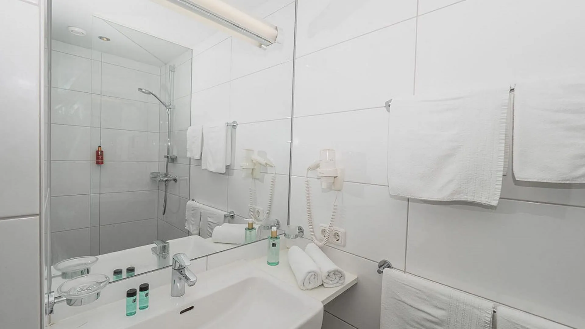 Helles Badezimmer mit Dusche, Waschbecken und Handtüchern.