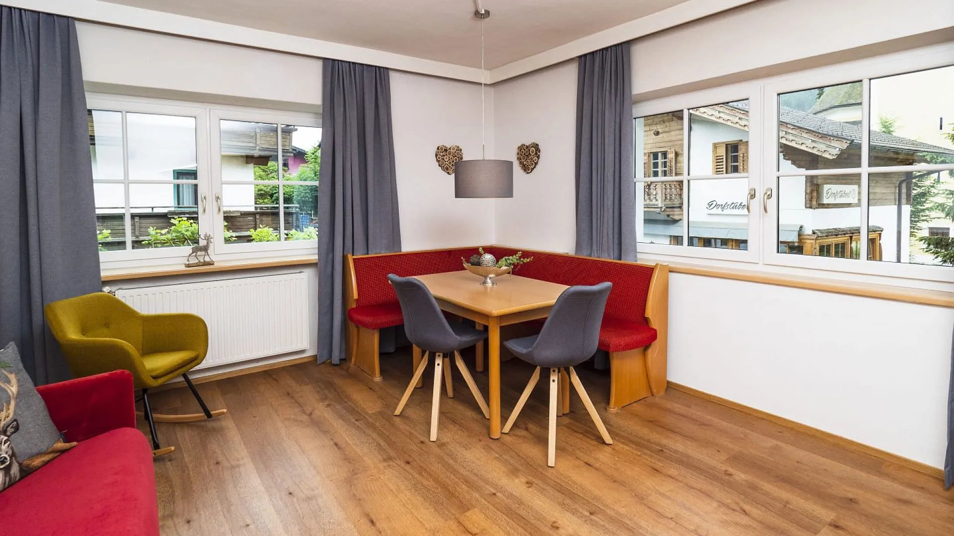 Helle Wohnung mit einem Essbereich, roten und gelben Stühlen und Fenstern.