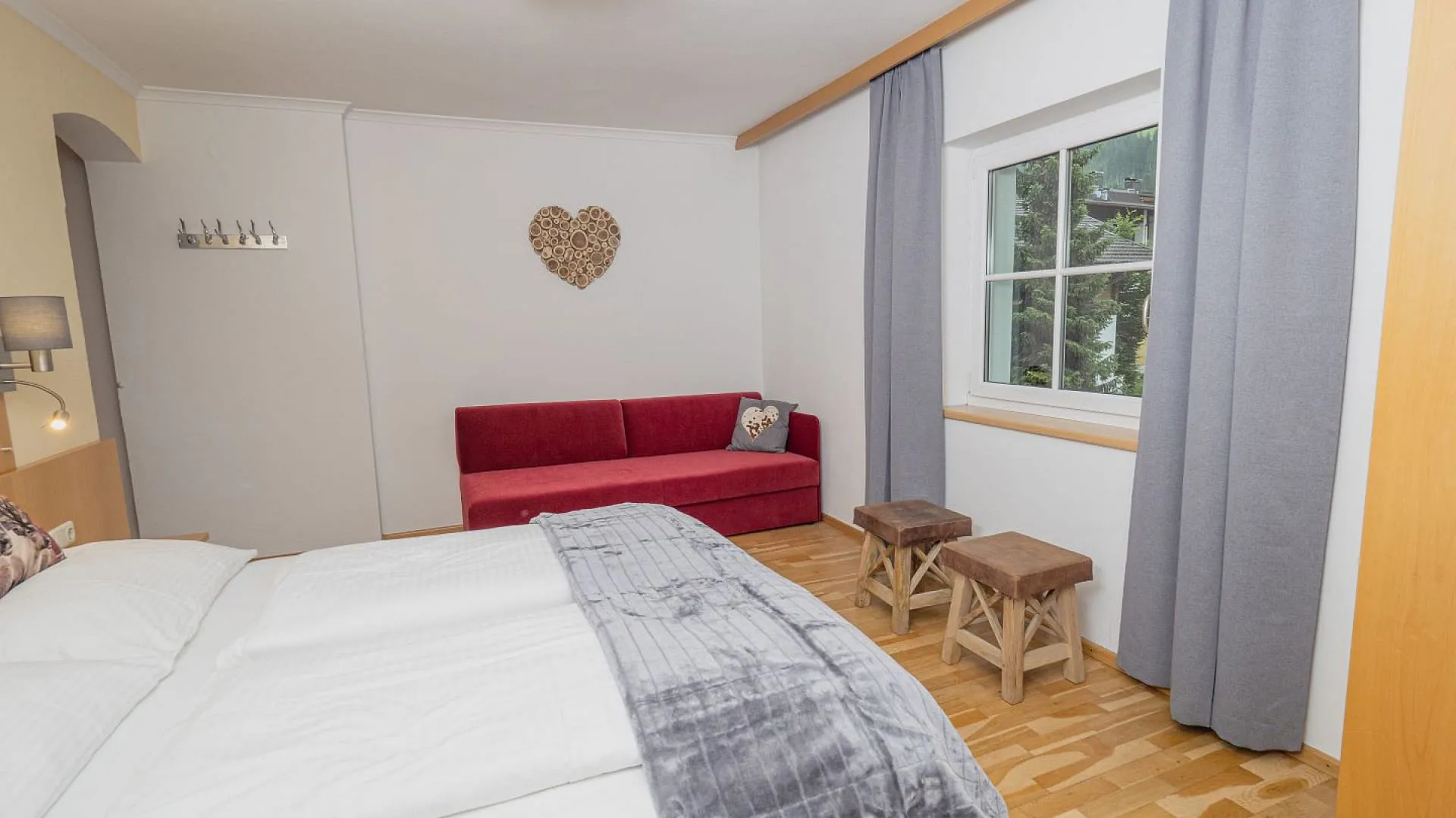 gemütliches Schlafzimmer mit rotem Sofa, Holzmöbel und großem Fenster