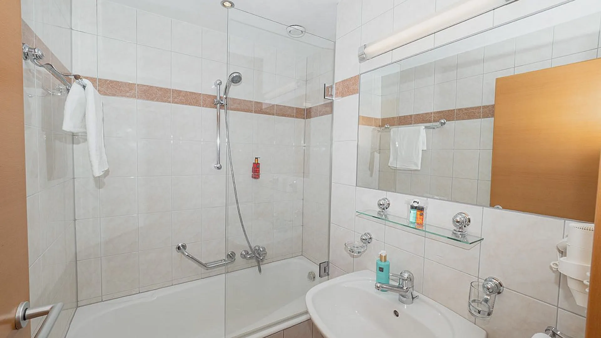 Badezimmer mit Dusche, Badewanne, Waschbecken und Spiegel
