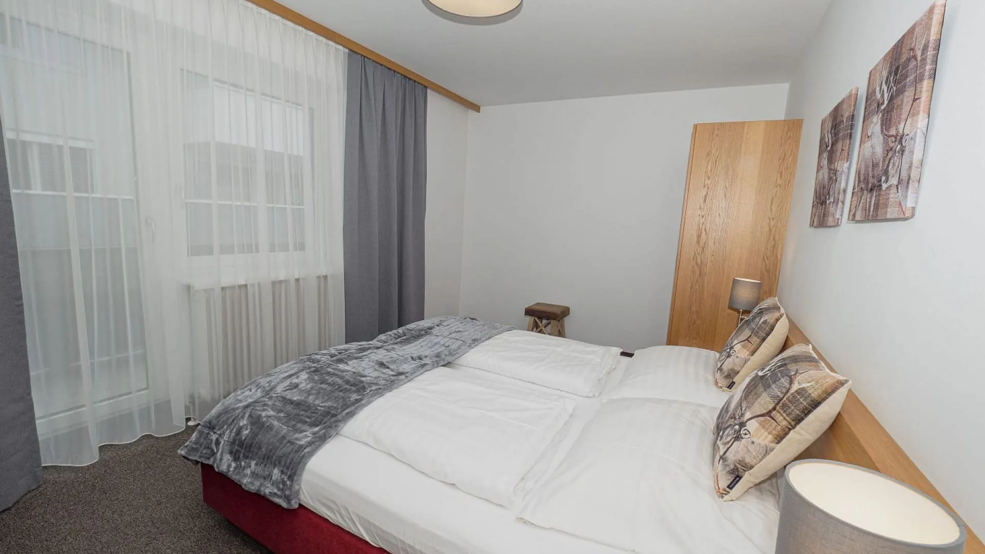 Helles Schlafzimmer mit einem Doppelbett, Lampen und Gardinen.
