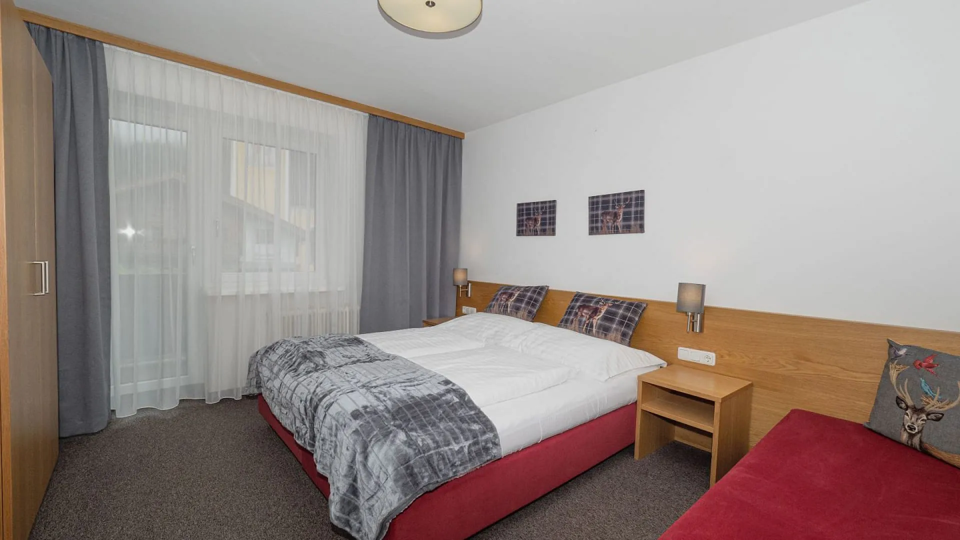 Helles Schlafzimmer mit Doppelbett und rotem Sofa.