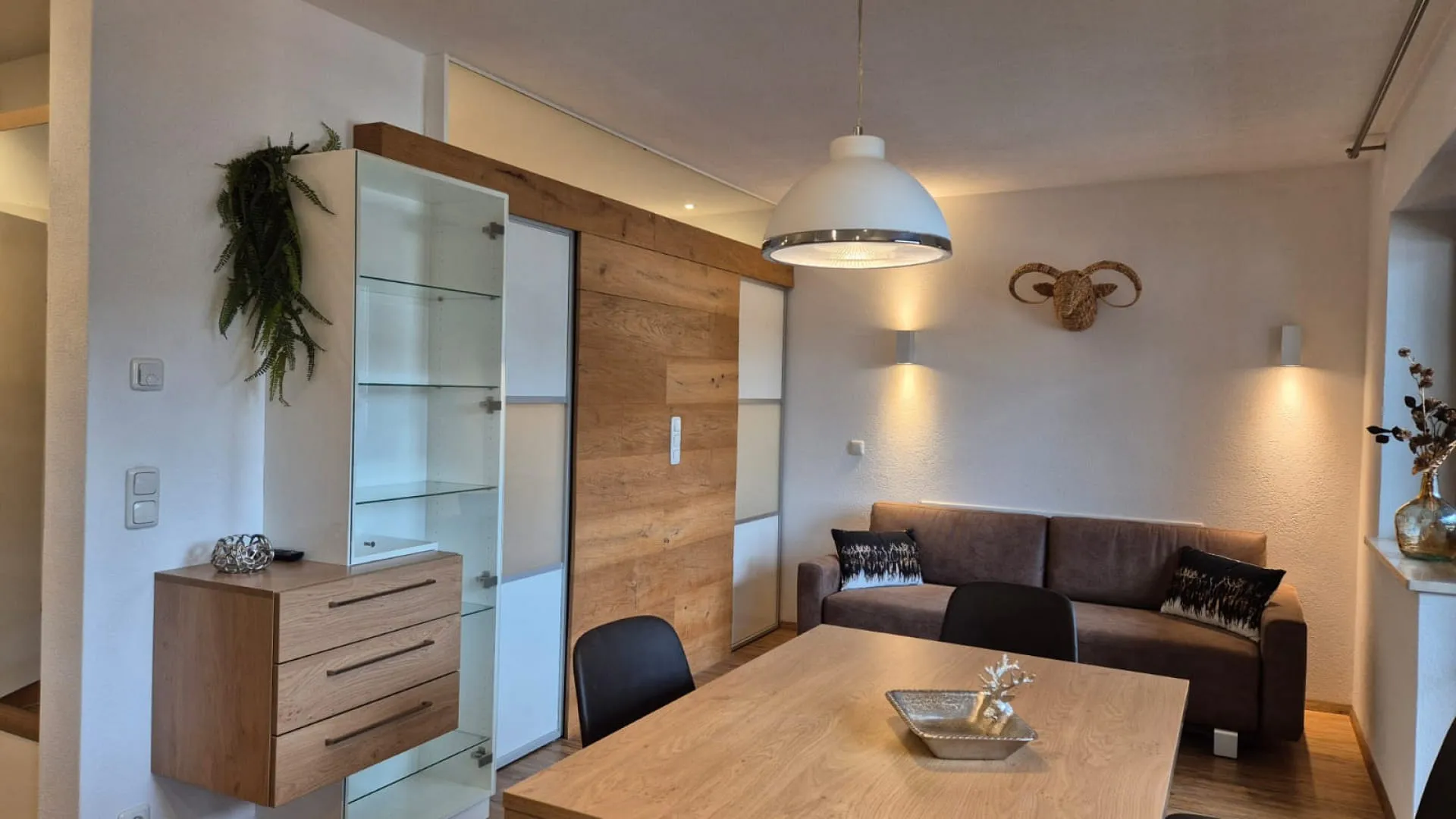 Modernes Wohnzimmer mit Couch, Esstisch und Holzregal.